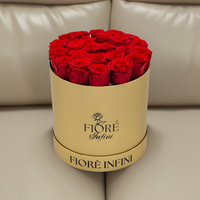 24 red roses in a gold box on a sofa