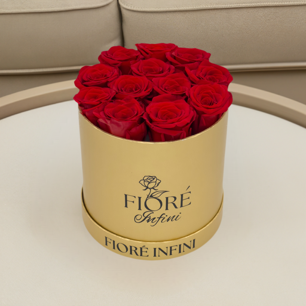 red forever rose arrangement in a gold box on a table