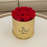 red forever rose arrangement in a gold box on a table