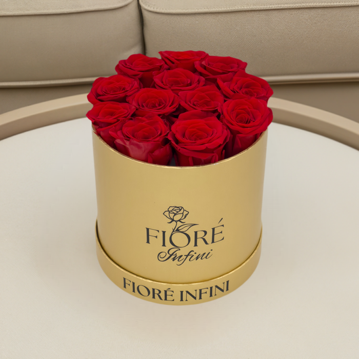 red forever rose arrangement in a gold box on a table