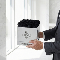 man holding black preserved roses